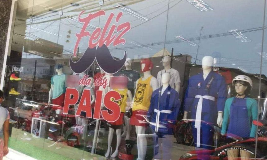 Vitrine de loja com decoração do Dia dos Pais, com manequins vestidos com roupas esportivas.