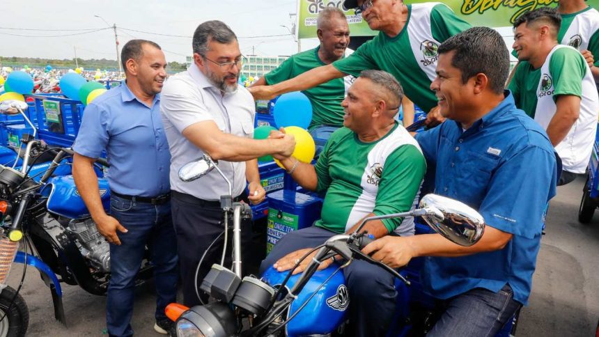Wilson Lima entrega triciclos a produtores rurais, com balões e outros homens presentes.