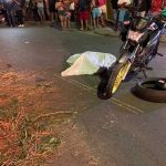 Acidente de trânsito com vítima fatal: motocicleta e corpo coberto na rua