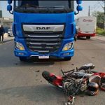 Acidente de trânsito: moto danificada após colisão frontal com carreta azul.