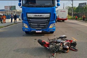 Acidente de trânsito: moto danificada após colisão frontal com carreta azul.
