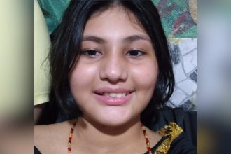 Adolescente sorrindo com cabelo escuro e colar.