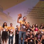 Apresentação em evento do Festival de Teatro da Amazônia, com pessoas no palco e mensagem.