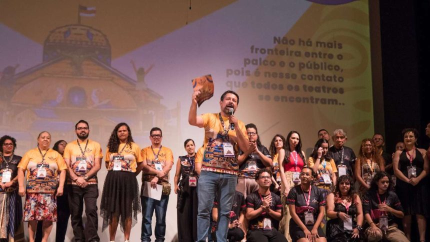 Apresentação em evento do Festival de Teatro da Amazônia, com pessoas no palco e mensagem.