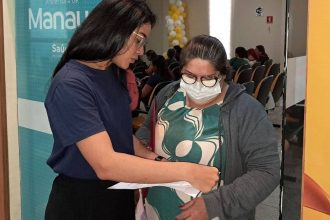 Assistente verifica documentos de pessoa para vacinação animal em Manaus.
