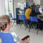 Atendimento em guichês da Manausprev com pessoas aguardando e funcionários em atendimento.
