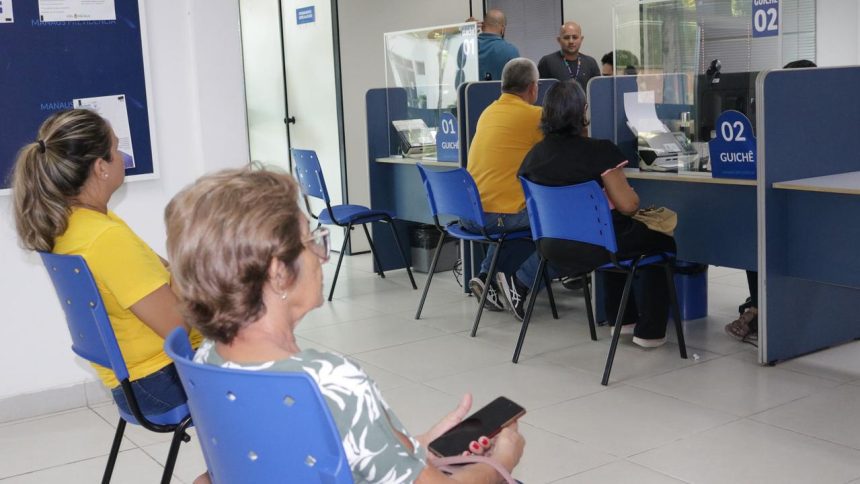Atendimento em guichês da Manausprev com pessoas aguardando e funcionários em atendimento.