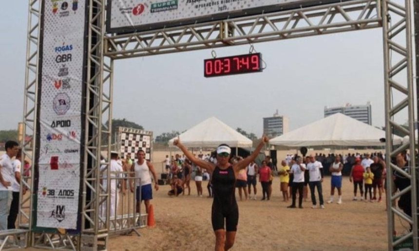 Atleta cruza a linha de chegada do Aquathlon Naval da Marinha do Brasil, com cronômetro marcando o tempo.