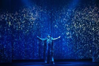 Atriz se apresenta em palco azul com efeitos, festival de teatro em Manaus.