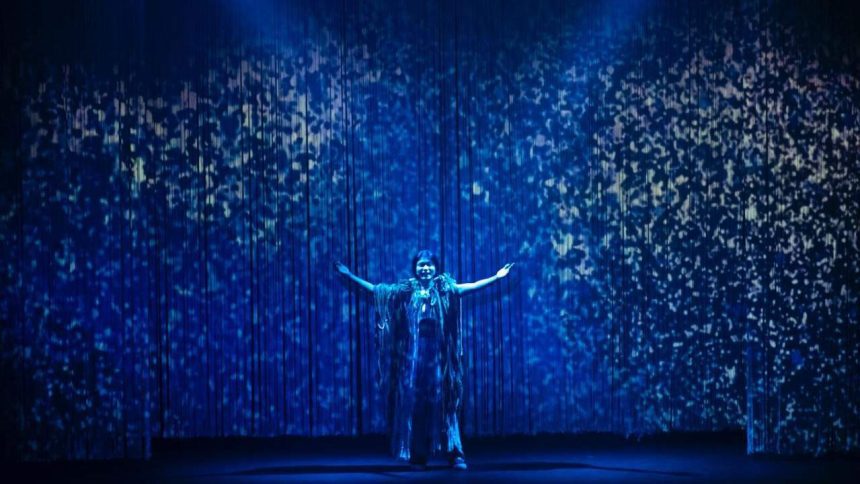 Atriz se apresenta em palco azul com efeitos, festival de teatro em Manaus.