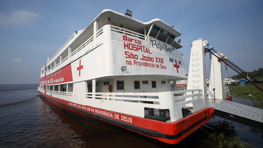 Barco hospital São João XXII, com a cruz vermelha, em um rio.