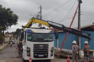 Caminhão com guindaste trabalha em poste de energia elétrica em Manaus.