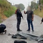Cena de acidente com vítima fatal: homem coberto por lona ao lado de motocicleta e policiais.