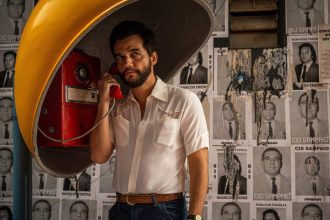 Cena de "O Agente Secreto", filme finalista do Brasil no Oscar 2026, com homem em cabine telefônica.