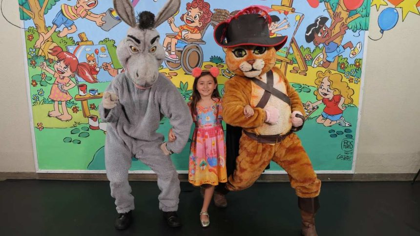 Criança com fantasias do Gato de Botas e Burro de Shrek em evento de doação de brinquedos em Manaus.