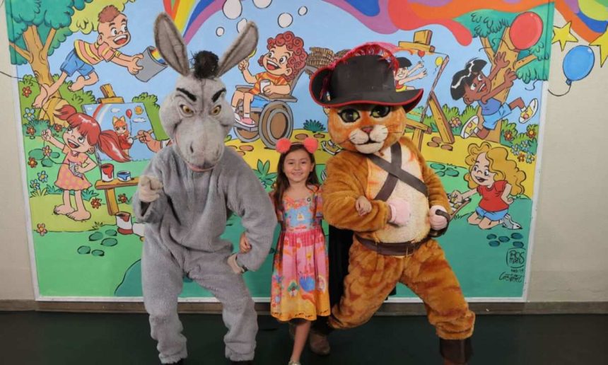 Criança posa com fantasias do Burro e Gato de Botas em evento.