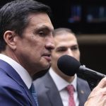 Deputado falando em evento, com microfone.