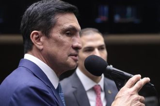 Deputado falando em evento, com microfone.