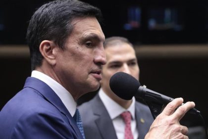 Deputado falando em evento, com microfone.