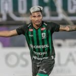 Edison Negueba, jogador de futebol do Juventude, celebra com os braços abertos.