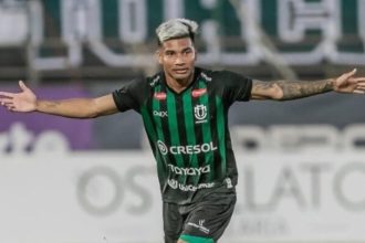 Edison Negueba, jogador de futebol do Juventude, celebra com os braços abertos.