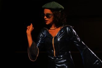 Ensaio da peça "Oceanos" com atriz usando roupa azul e óculos escuros