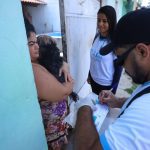 Equipe de vacinação animal em Manaus, com uma pessoa segurando um cachorro e outra preenchendo formulário.