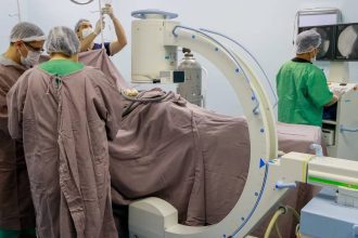 Equipe médica realiza procedimento cirúrgico em sala de operação, com equipamentos e monitores