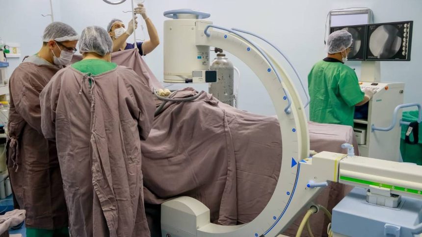 Equipe médica realiza procedimento cirúrgico em sala de operação, com equipamentos e monitores