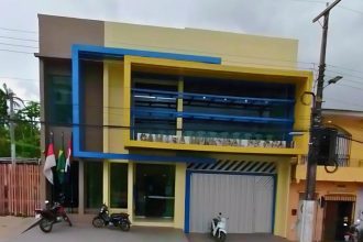 Fachada da Câmara Municipal de Coari, prédio com arquitetura moderna e bandeiras hasteadas.