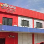 Fachada da distribuidora Adriane, com letreiro e cores vibrantes.