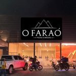 Fachada da pizzaria O Faraó, com estátua da esfinge e motos de entrega.
