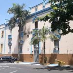 Fachada do Colégio Militar de Manaus em dia ensolarado, com carro e palmeiras.