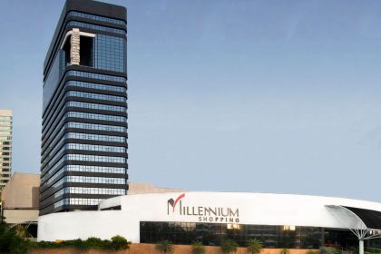 Fachada do Millennium Shopping, com edifícios modernos e céu azul ao fundo.