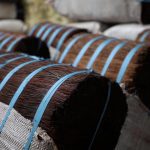 Fardos de piaçava amarrados com fitas azuis, prontos para transporte.