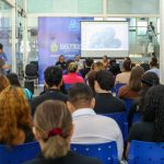 Feirão de Empregos no Sine com apresentação em tela para uma plateia atenta.