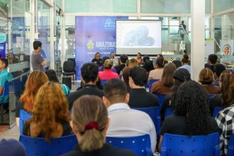 Feirão de Empregos no Sine com apresentação em tela para uma plateia atenta.