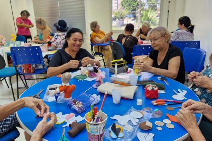 Grupo de mulheres em curso de artesanato, focadas em costura criativa, com materiais e projetos sobre a mesa.
