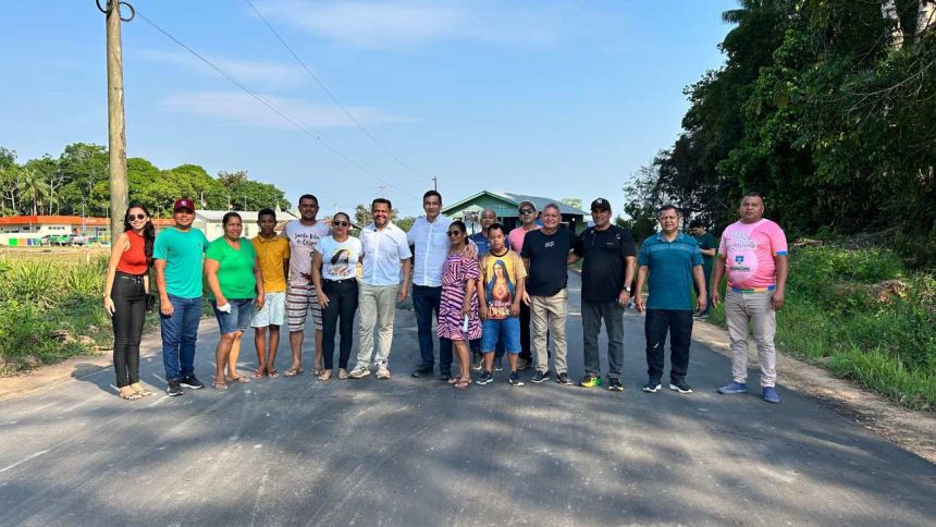 Grupo de pessoas posando para foto em estrada pavimentada, com céu azul ao fundo.