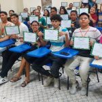 Grupo de pessoas sorrindo e segurando certificados após a conclusão de um curso.