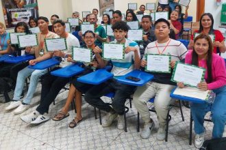 Grupo de pessoas sorrindo e segurando certificados após a conclusão de um curso.
