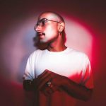 Homem com óculos e camisa branca em luz vermelha