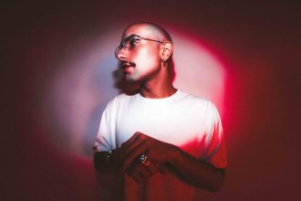 Homem com óculos e camisa branca em luz vermelha