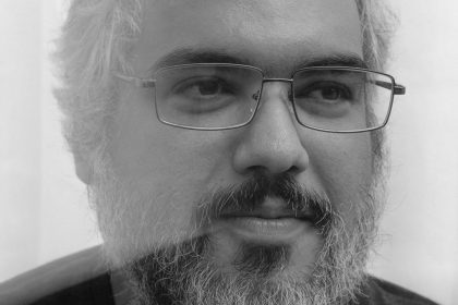 Homem de meia-idade com óculos e barba, em foto preto e branco.