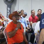 Homem fala ao microfone em evento sobre cursos gratuitos da Expoagro 2025 para o setor primário.