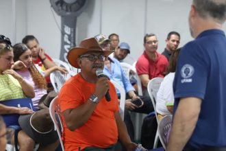 Homem fala ao microfone em evento sobre cursos gratuitos da Expoagro 2025 para o setor primário.