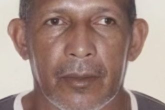 Homem idoso, pele morena, olhando para a câmera, possivelmente em busca de identificação.