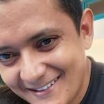 Homem sorrindo, possivelmente em contexto de denúncia de violência.