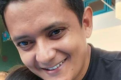 Homem sorrindo, possivelmente em contexto de denúncia de violência.
