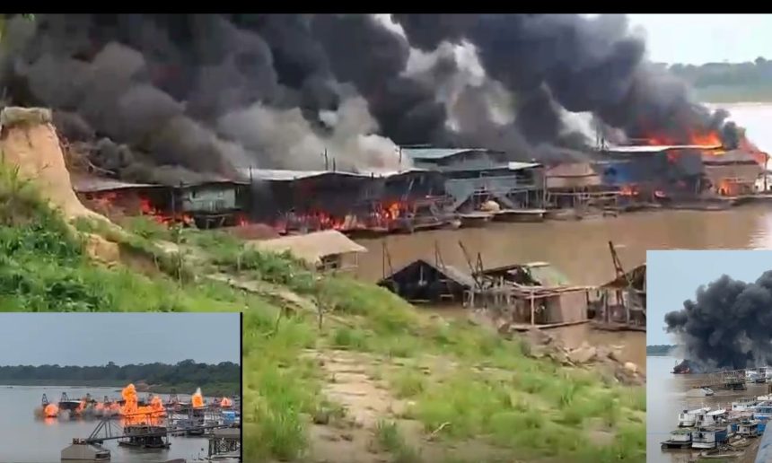 Incêndio em estruturas à beira-rio no Amazonas, com fumaça densa e fogo visível.